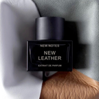 FBYMM New Leather parfumflesje met zwarte dop tegen een achtergrond van grijs en bruin leer