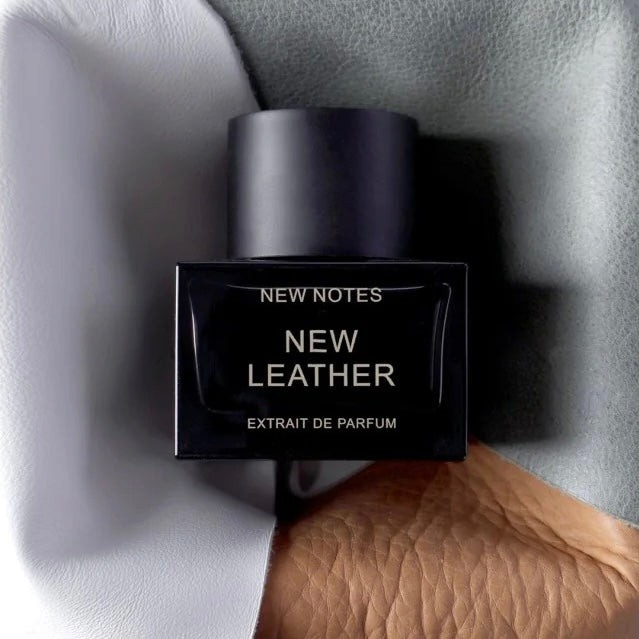 FBYMM New Leather parfumflesje met zwarte dop tegen een achtergrond van grijs en bruin leer
